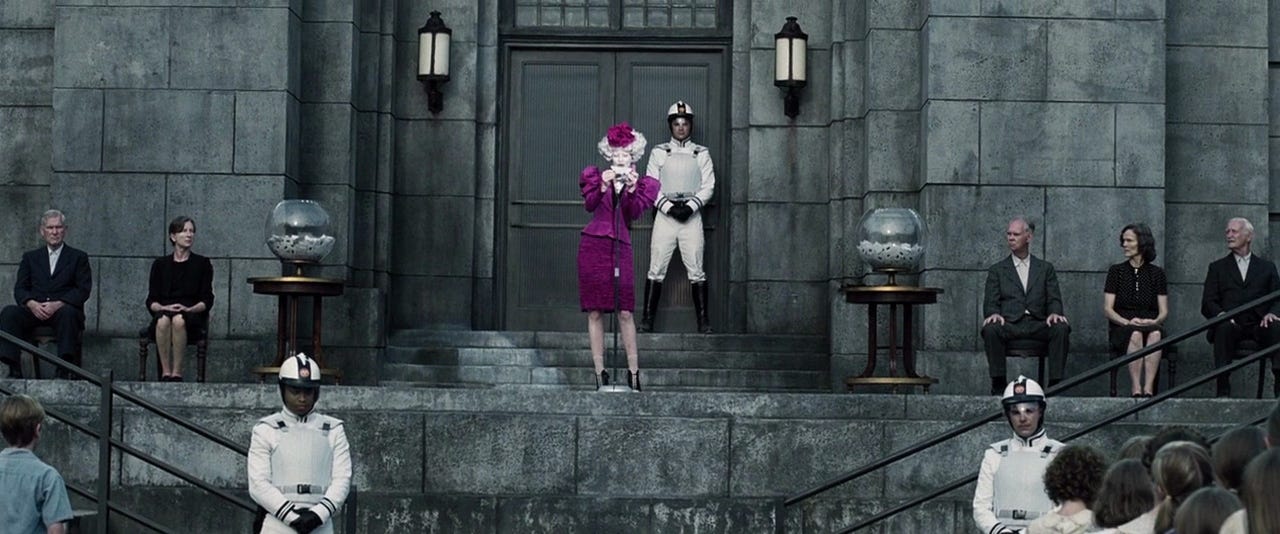 Effie Trinket's costume juxtaposed with District 12